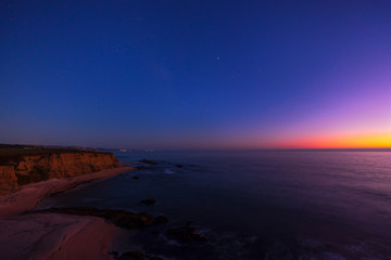 Dusk off the coast of Half Moon Bay, Northern California with the clifflike and beach and the pink...