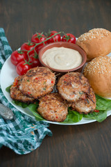 Cutlets from minced meat with paprika, tomatoes and herbs in a bowl on a white dish with a sauce. Wooden background.