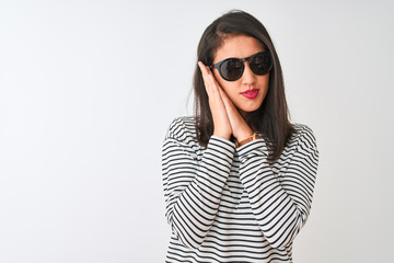 Fototapeta premium Chinese woman wearing striped t-shirt and sunglasses standing over isolated white background sleeping tired dreaming and posing with hands together while smiling with closed eyes.
