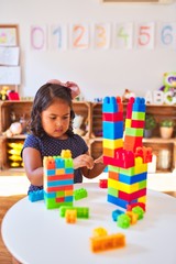 Beautiful toddler girl playing with construction blocks at kindergarten
