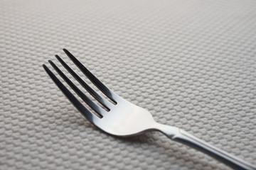modern silver stainless steel fork on a table with a white tablecloth.