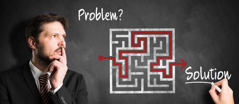 businessman thinking about how to solve a problem in front of blackboard with a drawn maze