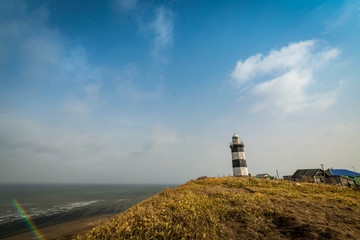 Fototapeta na wymiar lighthouse building on a hill overlooking the sea, striped lighthouse