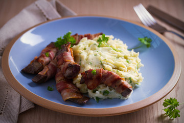 Beef liver wrapped in bacon with mash potato on blue table. horizontal image