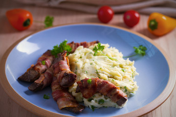 Beef liver wrapped in bacon with mash potato on blue table. horizontal image