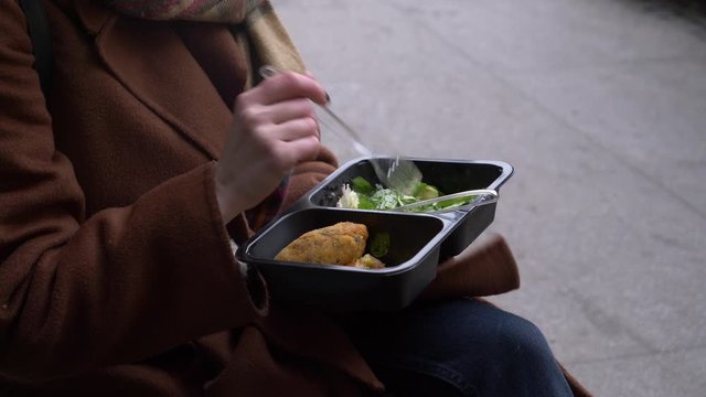 woman eating a satad on city beanch