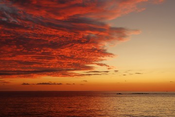 Fototapeta premium Sunset over the southern calm sea and scarlet thick clouds