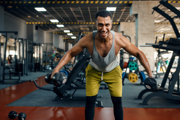 Fototapeta na wymiar Athlete doing exercise with dumbbells in gym