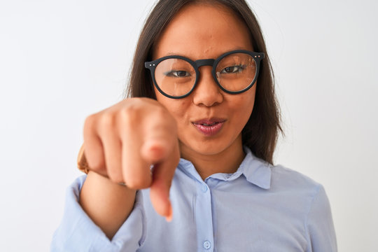 Young chinese woman wearing shirt and glasses standing over isolated white background pointing with finger to the camera and to you, hand sign, positive and confident gesture from the front