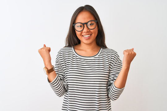 Young chinese woman wearing striped t-shirt and glasses over isolated white background celebrating surprised and amazed for success with arms raised and open eyes. Winner concept.