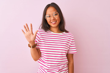Young chinese woman wearing striped t-shirt and glasses over isolated pink background showing and pointing up with fingers number five while smiling confident and happy.