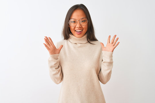 Young chinese woman wearing turtleneck sweater and glasses over isolated white background celebrating crazy and amazed for success with arms raised and open eyes screaming excited. Winner concept