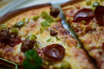 Pieces of delicious pizza with sausage lie on a plate. Selective focus, bokeh