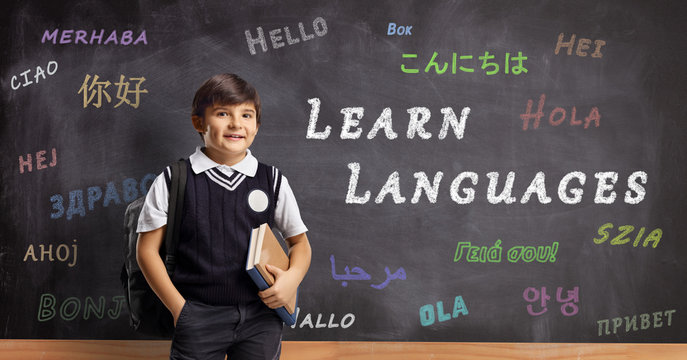 Schoolboy in front of a blackboard with hello written in different languages