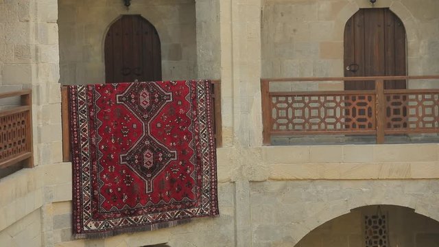 The courtyard of the old city in Baku. Oriental decoration and architecture. Panorama of balconies and a view of the curb on which a large oriental carpet dries