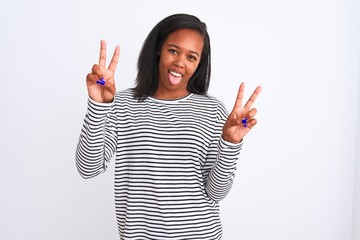 Beautiful young african american woman wearing winter sweater over isolated background smiling with tongue out showing fingers of both hands doing victory sign. Number two.