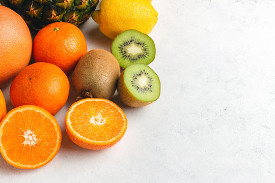 Assortment of tropical fruits, sliced and whole kiwi, orange, banana, tangerine, lemon, pineapple, grapefruit on textured white background © O.Farion