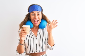 Tourist woman wearing neckpillow sleep mask drinking coffee over isolated white background very happy and excited, winner expression celebrating victory screaming with big smile and raised hands