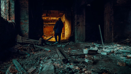 Man explorer with flashlight inside corridor or tunnel of ruined industrial building factory, horror and creepy atmosphere, vintage toned