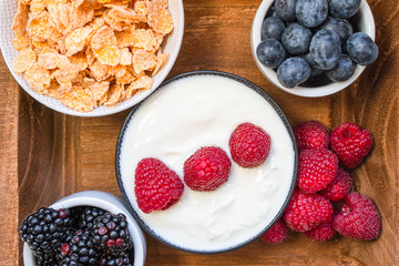 yogurt with whole fresh blueberries raspberries on wooden table. Healthy eating