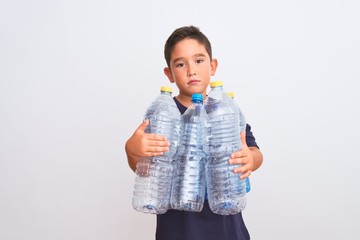 Beautiful kid boy recycling plastic bottles standing over isolated white background with a confident expression on smart face thinking serious