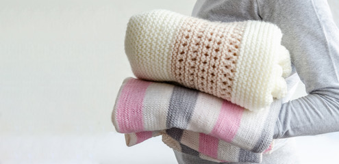 Female hands hold handmade knitted plaids from light natural yarn closeup on a white background.