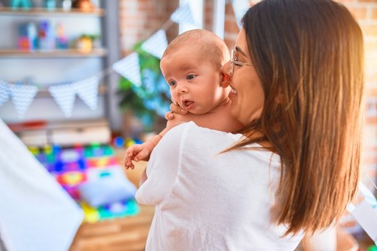 Young beautifull woman and her baby standing at home. Mother holding and hugging newborn