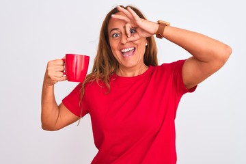 Middle age mature woman drinking a cup of hot coffee over isolated background with happy face smiling doing ok sign with hand on eye looking through fingers
