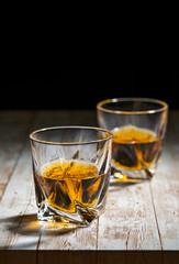 View of two filled whiskey glasses on a wooden bar top