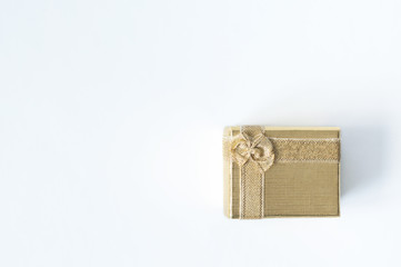 One small square golden gift box with a bow on a white background. Flat lay.