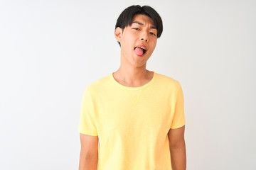 Chinese man wearing yellow casual t-shirt standing over isolated white background sticking tongue out happy with funny expression. Emotion concept.