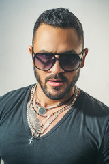 Obraz premium Charming man with sunglasses. Man face. Portrait of a handsome masculine man. Portrait of satisfied businessman against grey wall. Sunglasses. City fashion style.