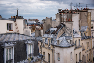 Old Paris rooftops with numerous chimmneys and TV antannae.