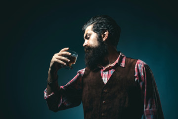 Elegant and stylish man in classical wear holding glass with wiskey in hand.