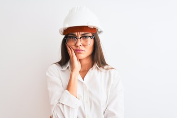 Young beautiful architect woman wearing helmet and glasses over isolated white background thinking looking tired and bored with depression problems with crossed arms.