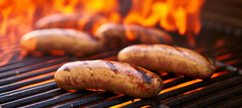 brats cooking over flaming barbecue grill