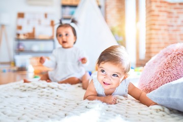 Obraz na płótnie Canvas Beautiful infant happy girls playing together at home kindergarten lying on blanket