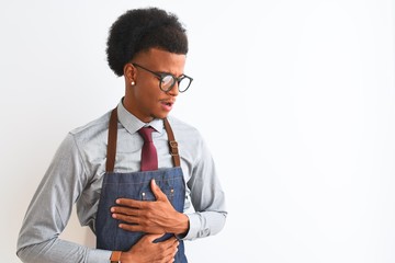 Young african american shopkeeper man wearing apron glasses over isolated white background with...