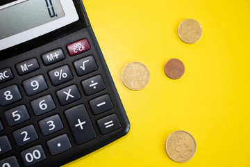 Flat lay or top view of black pen with calculator on vivid yellow background table with blank copy space, math, cost, tax or investment calculation.