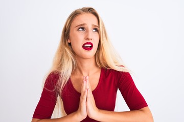 Young beautiful woman wearing red t-shirt standing over isolated white background begging and praying with hands together with hope expression on face very emotional and worried
