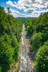 Fototapeta na wymiar A view from high above the Quechee Gorge in Vermont with a river running between rocky banks towards the mountains