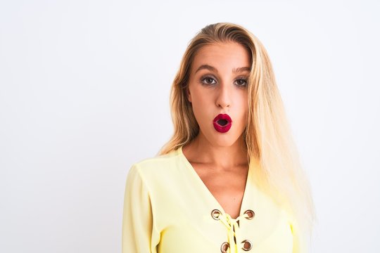 Young beautiful woman wearing elegant yellow t-shirt standing over isolated white background scared in shock with a surprise face, afraid and excited with fear expression
