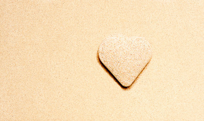 Heart symbol on a beach sand with soft sand background