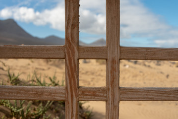 Close up of wooden vintage fence. Beach and high mountains in the background. Cofete, Fuerteventura. 