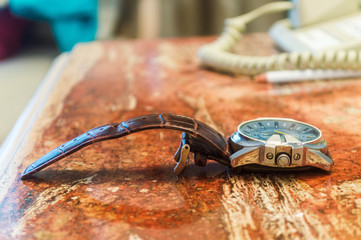 reloj con acabados plateados y azules con pulsera de cuero. Reloj sobre buró. Concepto de negocios. Lujo y Elegancia. 