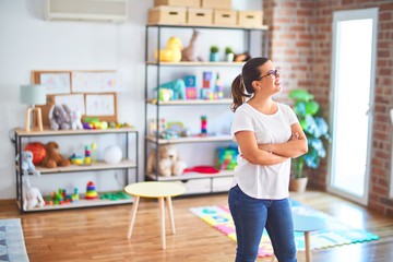 Young beautiful teacher wearing glasses standing at kindergarten