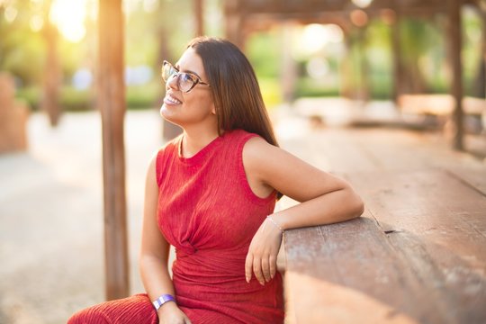 Young beautiful girl smiling happy and confident walking at the town park, standing with a smile on face