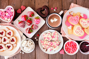 Valentines Day table scene of assorted sweets and cookies. Top view over a rustic wood background....