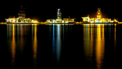 Fototapeta na wymiar A big commercial harbor at night with oil rigs docked at a repair wharf.