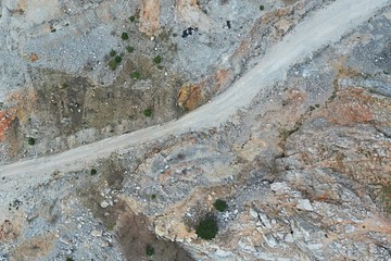 Aerial top down view of dirt road in limestone opencast mine with some scarce vegetation around